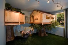 a tree house built into the side of a wall in a room with green grass