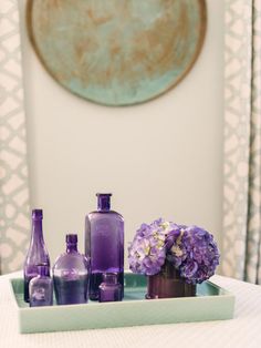 purple vases and bottles are sitting on a tray