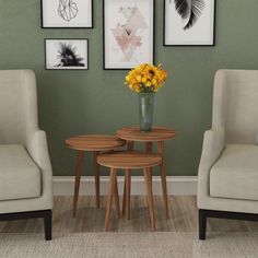 two chairs and a table with flowers on them in front of some framed pictures hanging on the wall