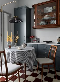 a dining room table with two chairs and a checkered floor in front of it