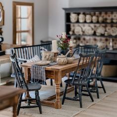 a wooden table with chairs around it in a room filled with other furniture and decor