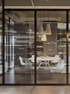 an office with glass partitions and white tables in the center, surrounded by chairs