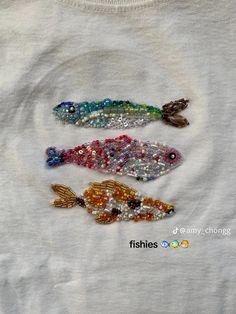 three different colored fish on a white t - shirt with sequins and beads