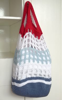 a crocheted bag hanging from a hook on a white door handle with red, white and blue handles