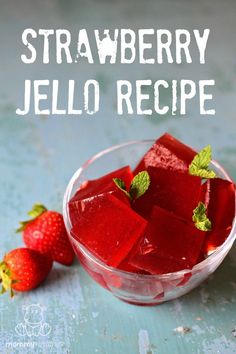 strawberry jello recipe in a glass bowl with strawberries next to it on a blue surface