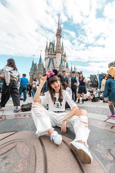 a woman sitting on the ground in front of a castle