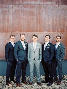 a group of men standing next to each other wearing suits and ties on top of rocks