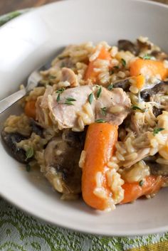 a white bowl filled with rice, carrots and meat on top of a table