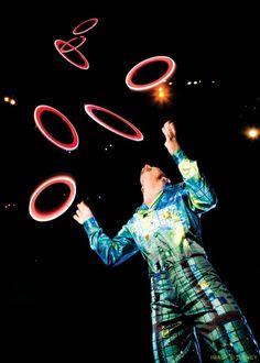 a man juggling circles in the dark