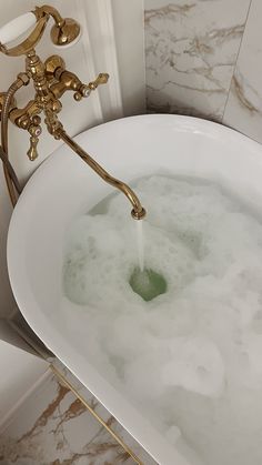 a bathtub filled with water next to a gold faucet