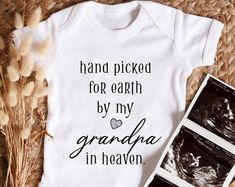 a baby bodysuit that says hand picked for earth by my grandma in heaven next to some dried grass