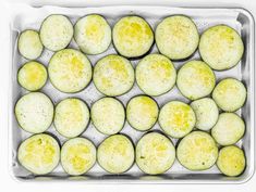 an overhead view of peeled cucumbers in a baking pan on a white surface