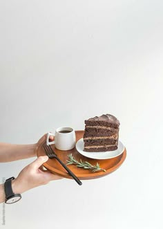 a person holding a plate with a piece of cake on it and a cup of coffee