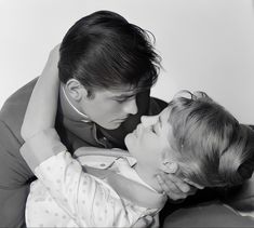 a black and white photo of a woman holding a child with her head on her shoulders