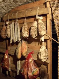 there are many different types of food hanging on the wall in this room, including hams and potatoes