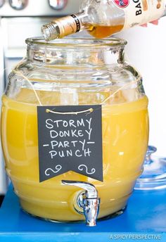 a glass jar filled with liquid sitting on top of a blue counter next to a sign that says stormy donkey party punch