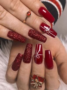 a woman's hands with red and gold nail polishes on their nails, holding a