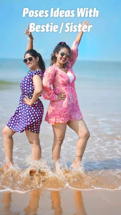 two women in colorful dresses standing on the beach with their arms up and legs crossed