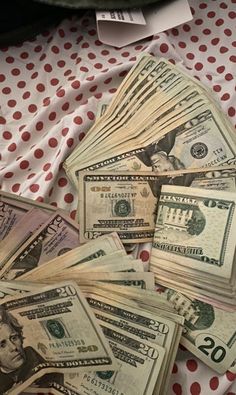 a pile of twenty dollar bills sitting on top of a red and white table cloth