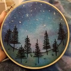 someone is holding up a small embroidery art piece with trees and stars in the sky