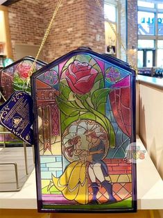 a stained glass window hanging from the side of a counter in a store with flowers on it