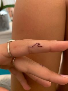 a woman's hand with a small wave tattoo on it