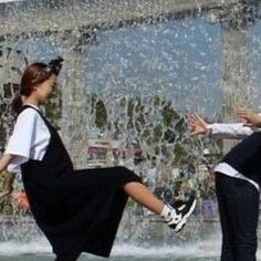 two people are dancing in front of a fountain with water spouting from it