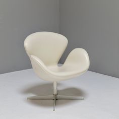 an egg chair sitting on top of a white floor next to a gray wall in a room