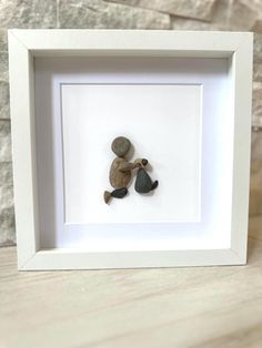 two pebbles in a white frame on a table