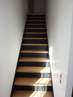 the stairs are made of wood and have black strips on them, with light coming through