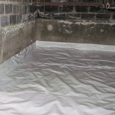 a cat is sitting on top of a sheeted bed in the corner of a room