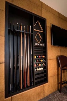 a wall mounted billiards rack with pool cues and cues in front of a flat screen tv