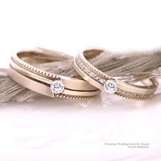 two gold wedding bands with diamonds on them and a tassel around the band are laying next to each other