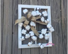 a wreath made out of cotton is hanging on a wooden fence