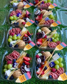 several plastic trays filled with different types of food on top of a grass covered field