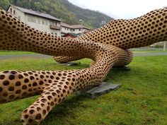 two large cheetah sculptures sitting on top of a lush green field