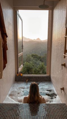 a woman sitting in a bathtub looking out the window