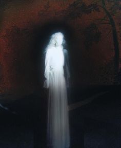 a ghostly woman standing in front of a dark background