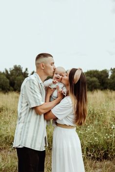 a man and woman kissing while holding a baby