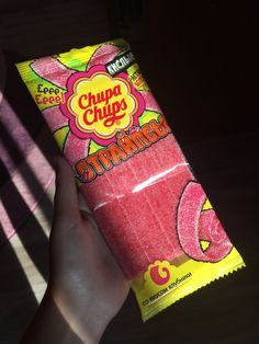 a person holding up a pink candy bar in their hand with the word chupa chups written on it