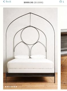 an iron bed frame with white sheets and pillows on the bottom, in front of a wall