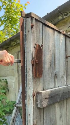 a person holding a wrench in front of a wooden door with rust on it