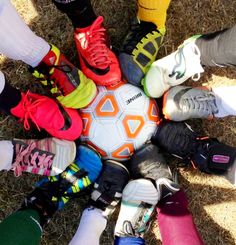 a group of people standing next to each other in front of a soccer ball on the ground