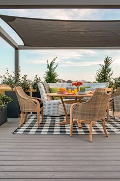 an outdoor dining table and chairs on a wooden deck with black and white checkered rug