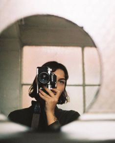 a woman taking a selfie in front of a mirror with a camera on it