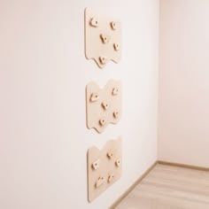 three wooden pegs are mounted to the wall in an empty room with wood flooring