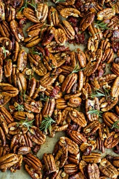 pecans with rosemary sprigs and dried cranberries on a baking sheet