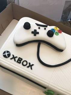 a cake shaped like a video game controller on top of a box with the word xbox written on it