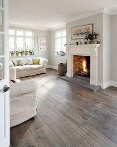 a living room with wood floors and a fire place in the center, on instagram