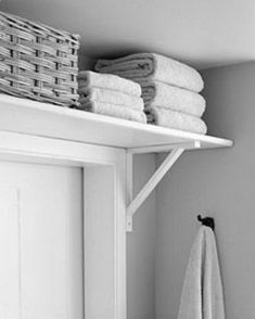 towels are stacked on top of the shelf above the door in this black and white photo